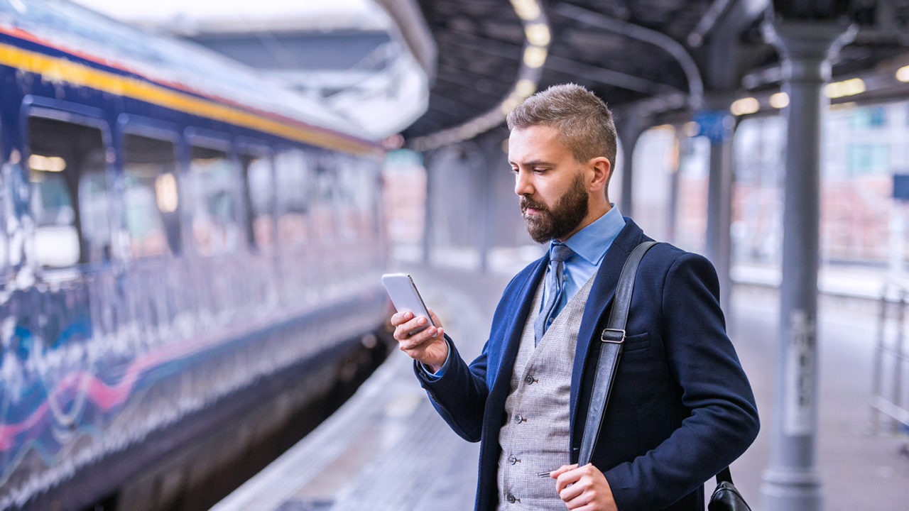 Business man at a railway station on his smartphone