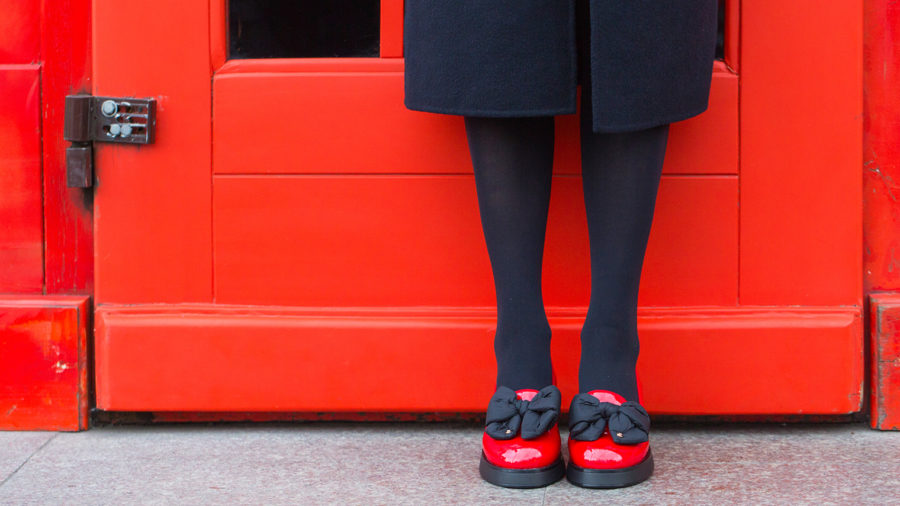 Woman wearing red shoes in front of a red door