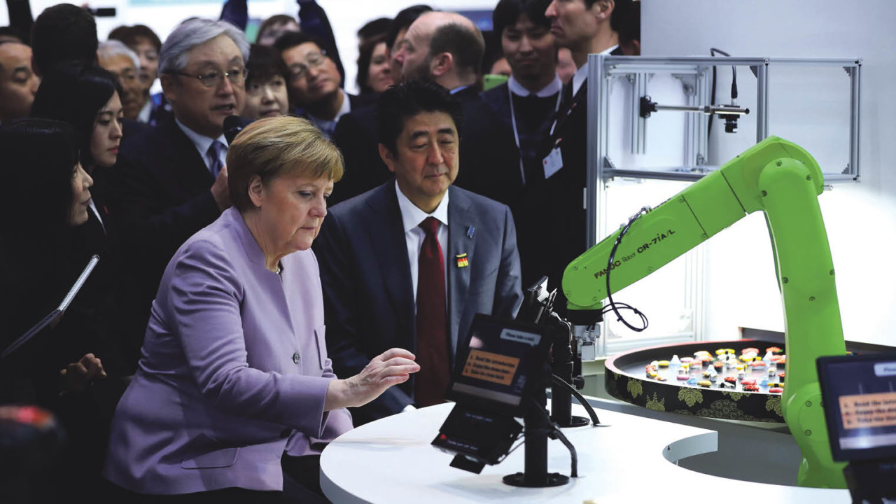 German and Japanese leaders Angela Merkel and Shinzo Abe watch a robotic arm serving sushi at the CeBIT 2017 tech fair in March