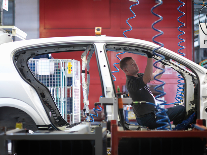 Worker Assembling Car On Production Line