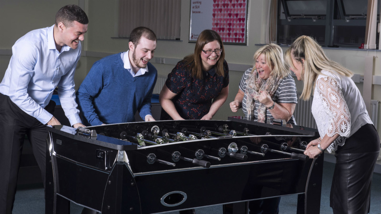Employees of South Liverpool Homes playing table football