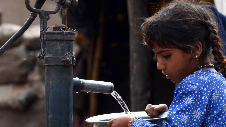 Young girl filling a pot from a water hand pump in Lahore, Pakistan