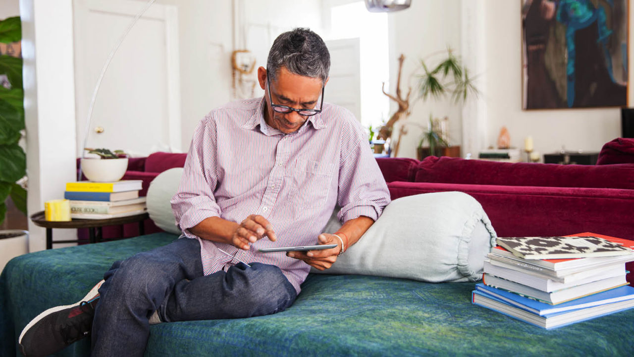 Man sitting on couch using tablet