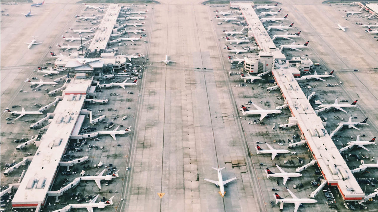 bird's eye view shot of many aeroplanes parked in rows on airfield