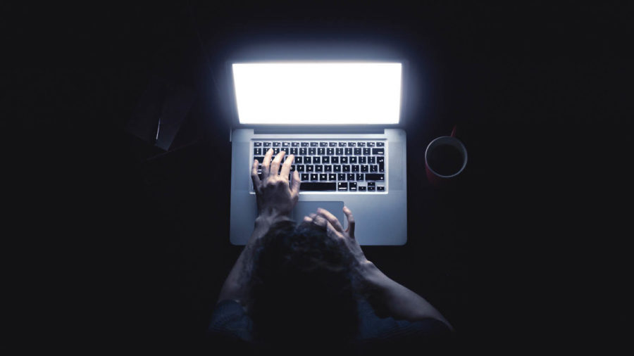 hacking back on glowing laptop in dark room