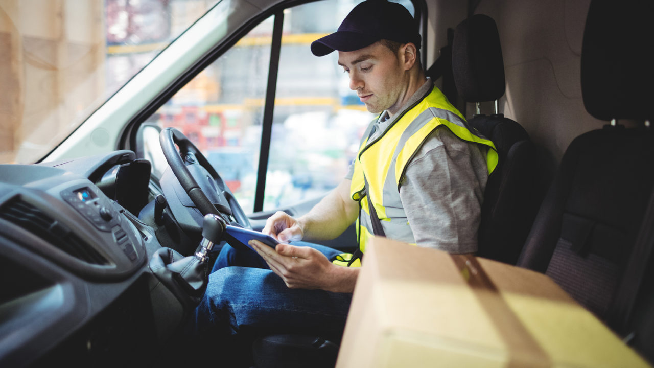 man from parcel delivery companies looking at tablet in truck