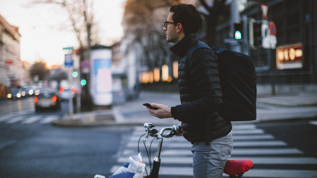 Man standing with bicycle holding phone