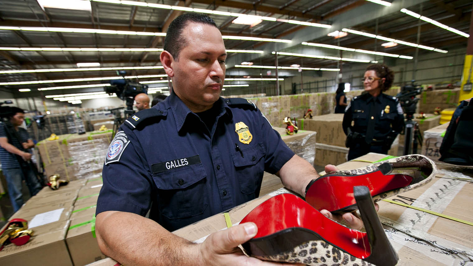 US Customs and Border Protection official examining a pair of counterfeit Christian Louboutin shoes