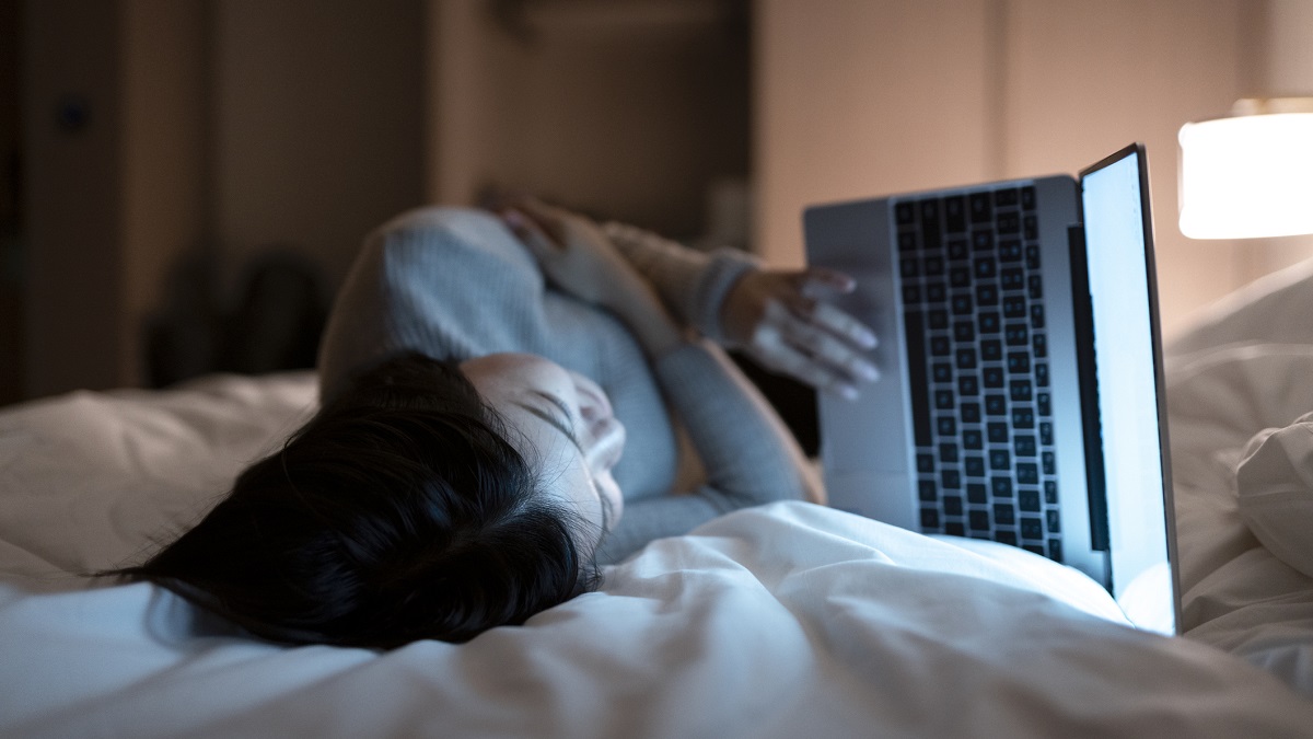 Woman working on her laptop while lying in bed