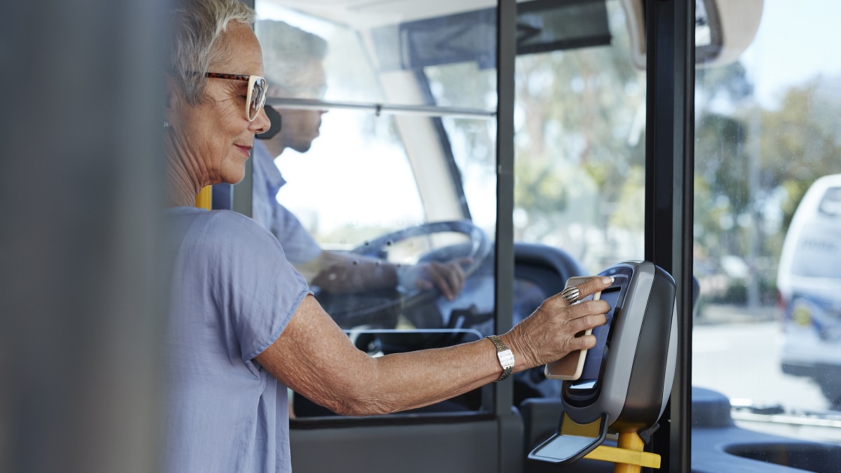 Mature woman using smartphone to pay for public bus ride