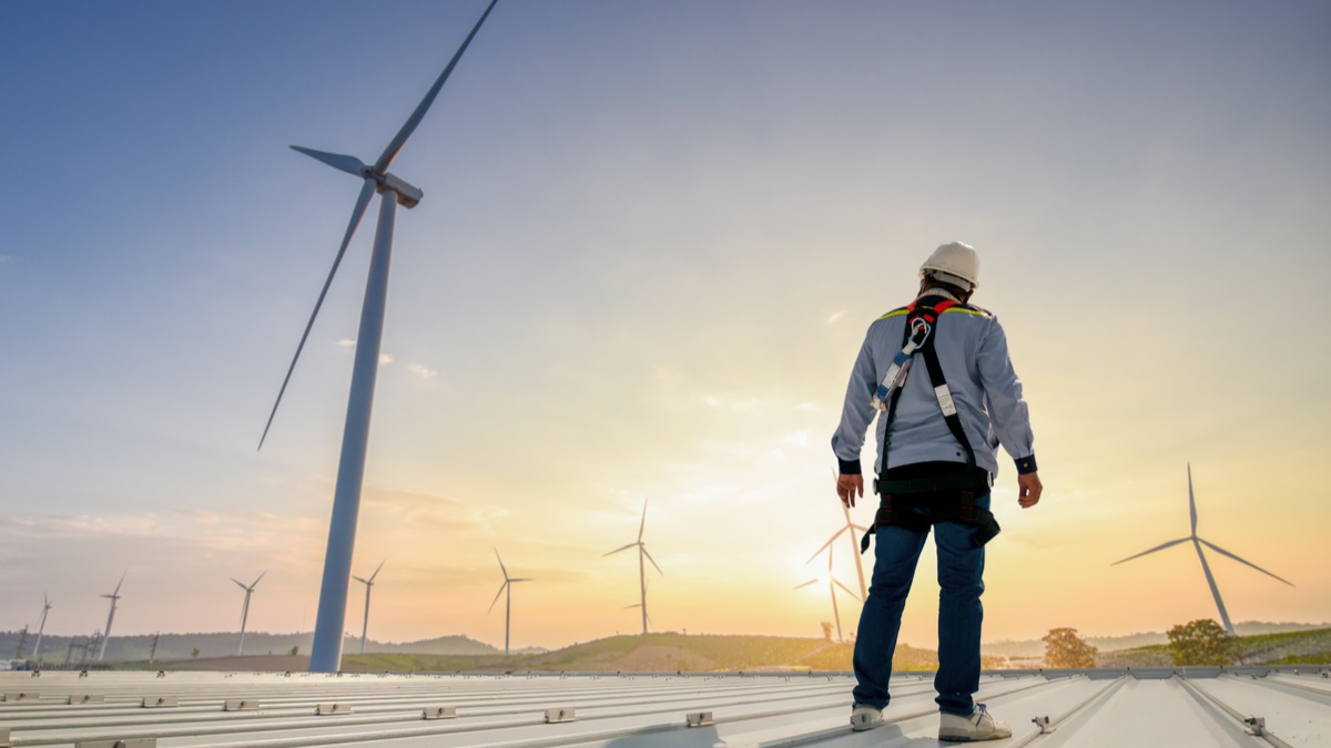 Man in hard hat standing by a windmill