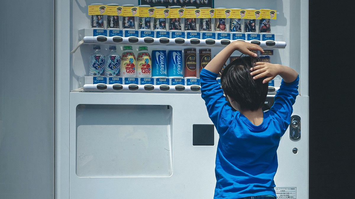 little boy trying to choose drink from vending machine