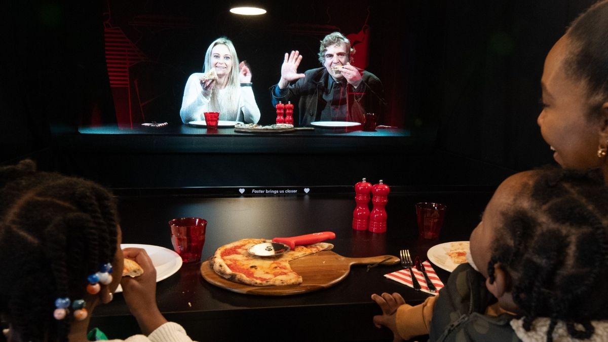 People share a pizza with friends projected via hologram in Virgin Media's innovative marketing campaign