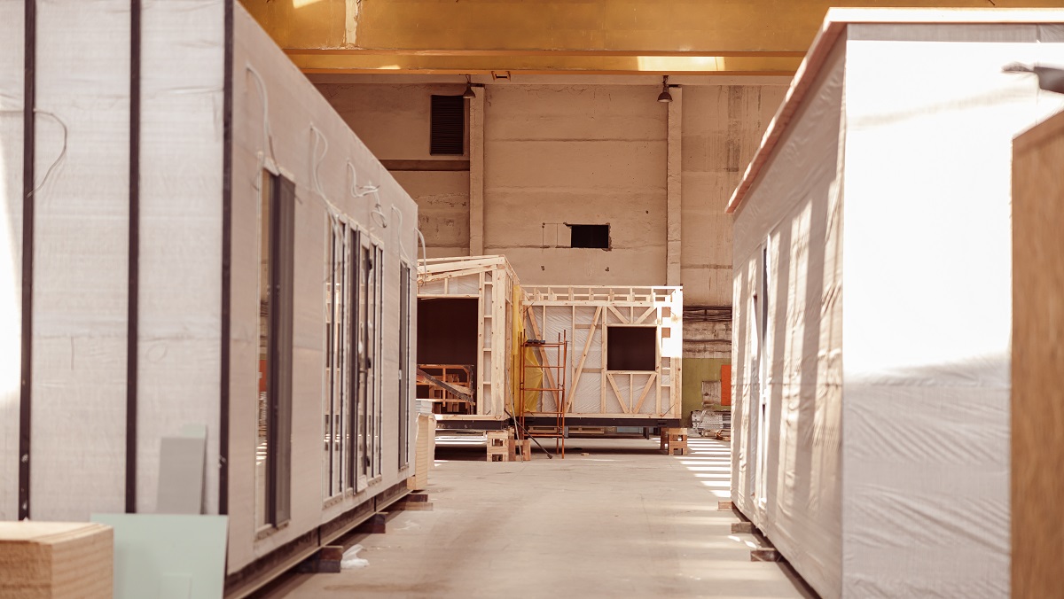 Building with concrete floor, construction materials and two mobile cabins with panel siding and glass doors