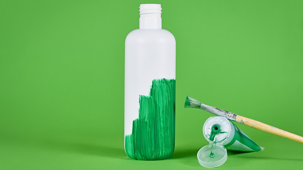 Greenwashing concept with white plastic bottle being painted green