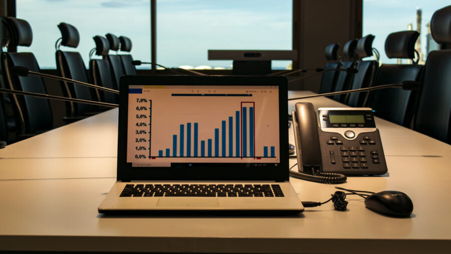 Computer with chart measuring growth sitting on the table of a modern boardroom