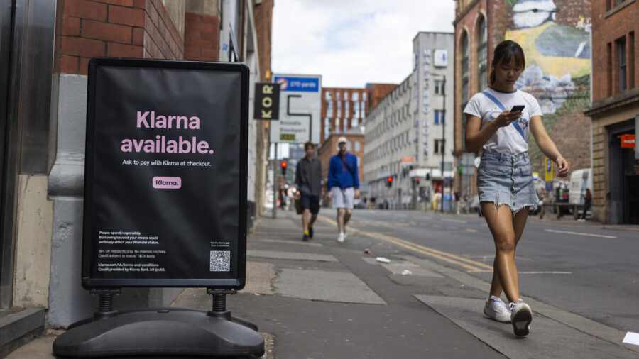 Woman walks by an advertisement for Klarna, a buy-now-pay-later provider