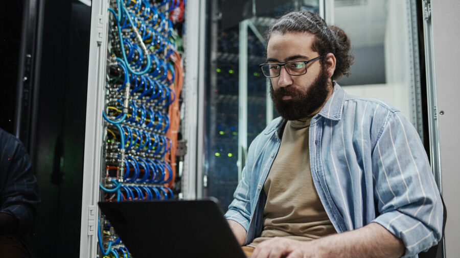 IT expert working on a laptop in a server room