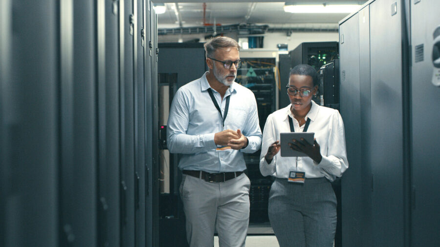 Two cybersecurity professionals having a discussion in a server room
