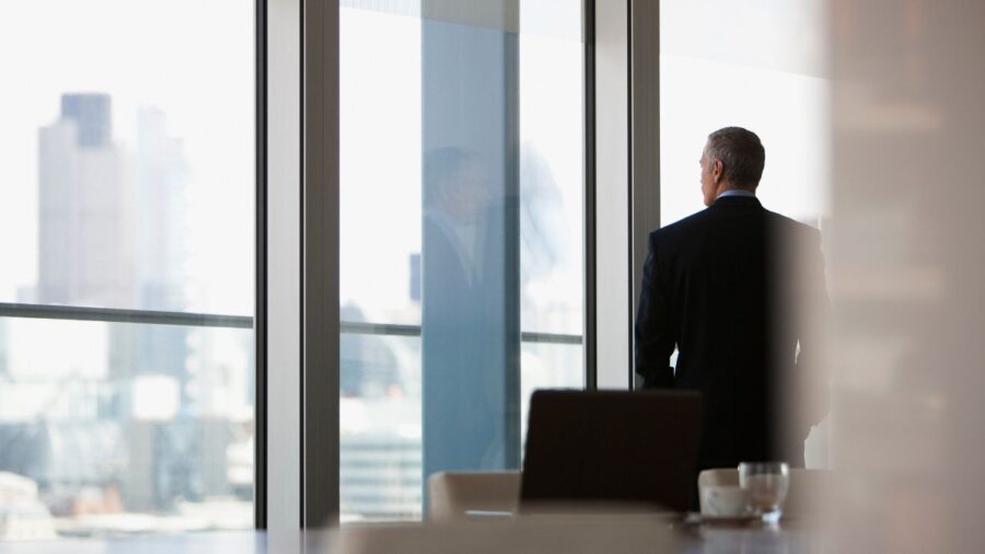 CEO in high-rise office looks out over the city