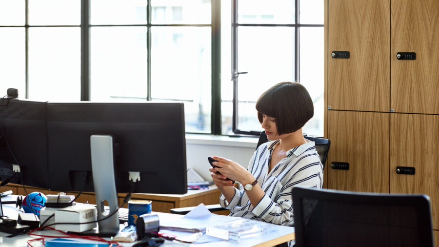 Businesswoman At Desk Using Mobile Phone